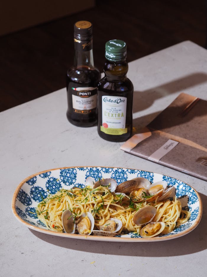 Services Delicious Italian spaghetti alle vongole with clams and olive oil on a decorative plate.
