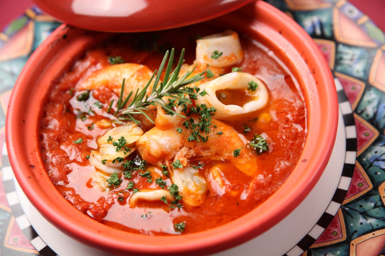 Home Savor this flavorful seafood stew with squid and shrimp in a rich tomato broth.